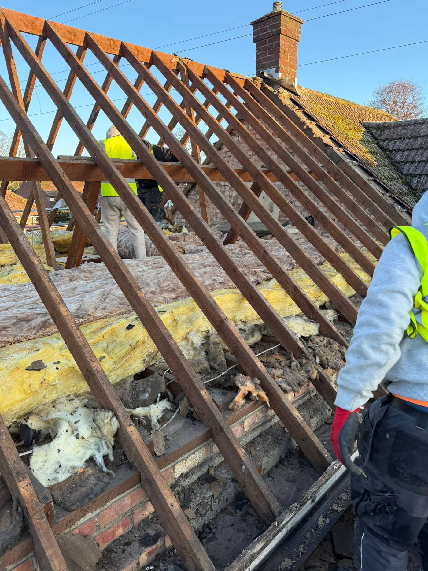 Roof stripped back to rafters with operatives working